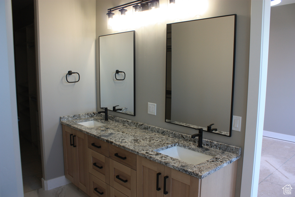 Bathroom featuring double vanity and marble look tile flooring