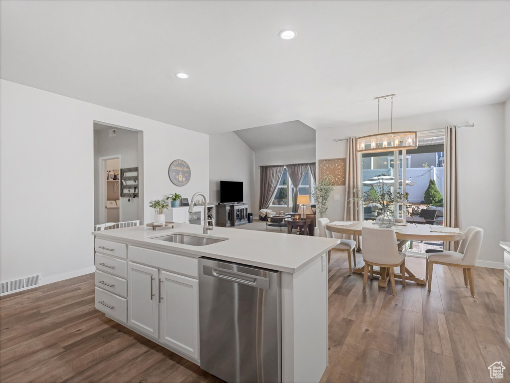 Kitchen featuring dishwasher, light countertops, wood finished floors, white cabinetry, and pendant lighting