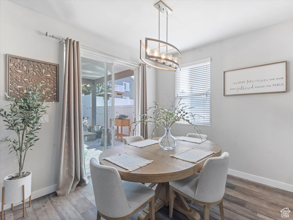 Dining space with a chandelier, healthy amount of natural light, and wood finished floors