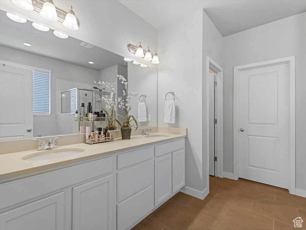 Bathroom featuring double vanity, tile patterned flooring, and a stall shower
