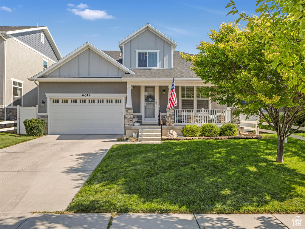 View of front of home featuring a porch, a garage, board and batten siding, driveway, and stone siding