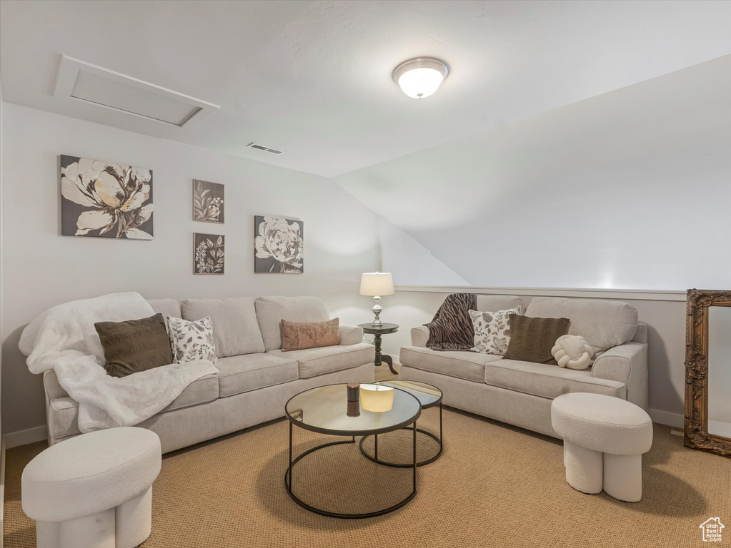Carpeted living room with lofted ceiling and attic access