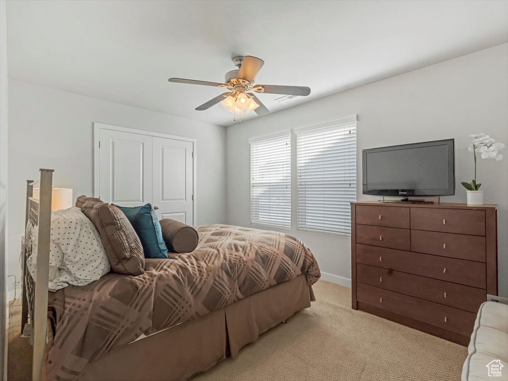 Bedroom featuring light colored carpet, ceiling fan, and a closet