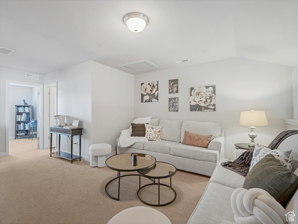 Living area with attic access, carpet floors, and vaulted ceiling