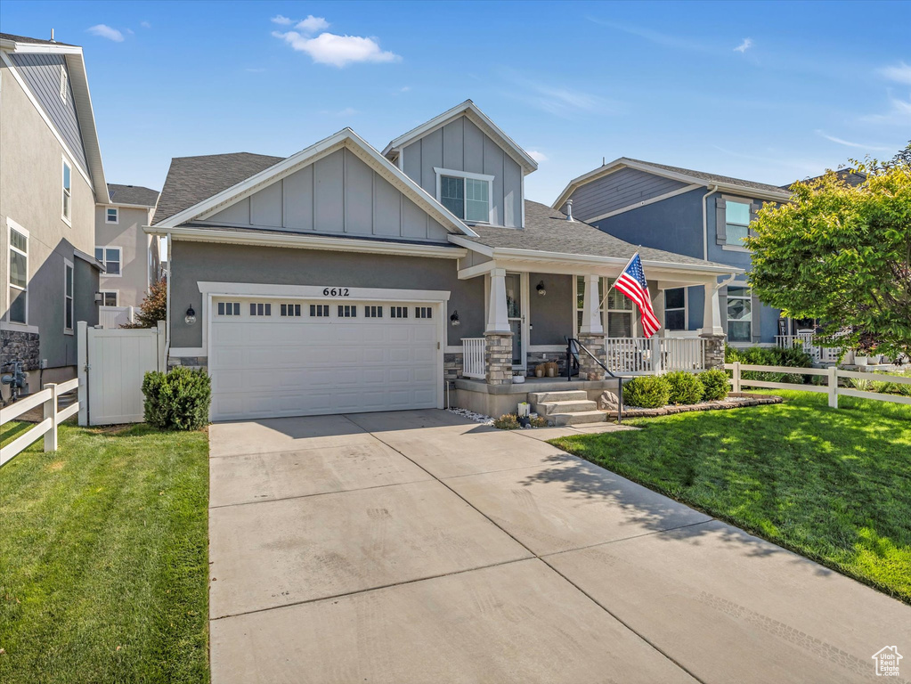 Craftsman-style house with a porch, board and batten siding, concrete driveway, a garage, and stone siding