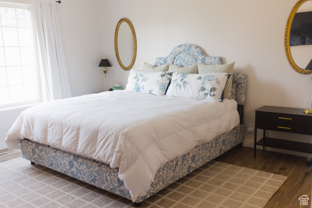 Bedroom with wood finished floors and multiple windows