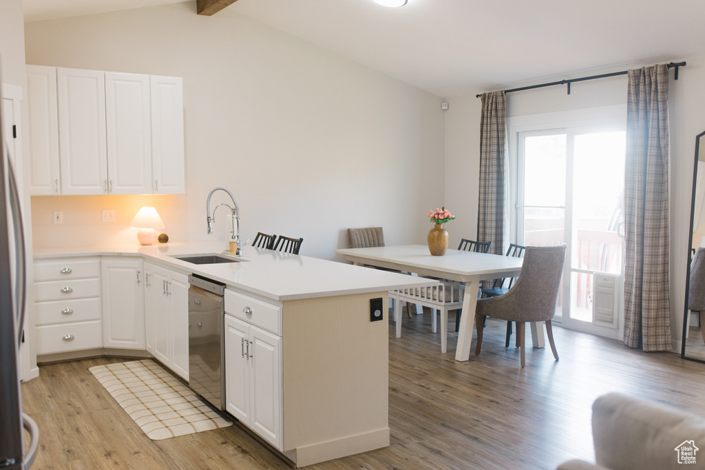 Kitchen with stainless steel dishwasher, a peninsula, light wood-style flooring, white cabinets, and light countertops