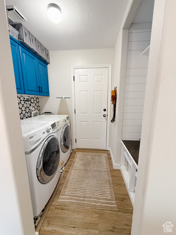 Laundry area featuring washer and clothes dryer, cabinet space, and light wood-style floors