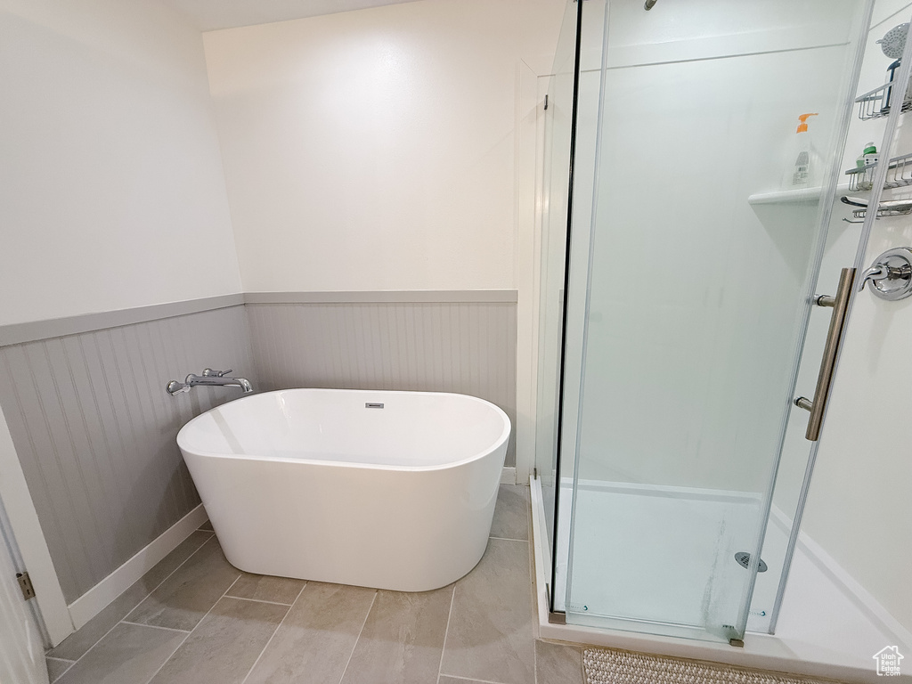Full bathroom featuring a wainscoted wall, a shower stall, and a freestanding tub
