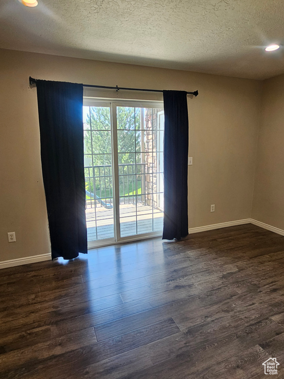 Unfurnished room featuring a textured ceiling, dark wood-style floors, and recessed lighting
