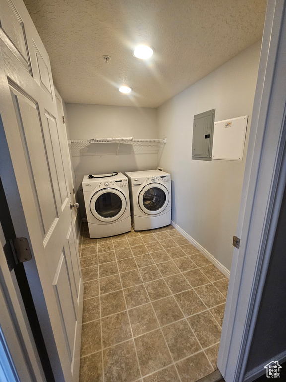 Laundry area with electric panel, a textured ceiling, independent washer and dryer, and recessed lighting