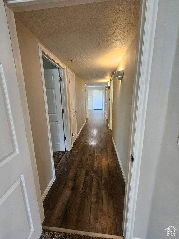 Corridor featuring dark wood-style floors and a textured ceiling