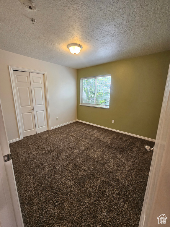 Carpeted spare room with a pendent fire sprinkler and a textured ceiling