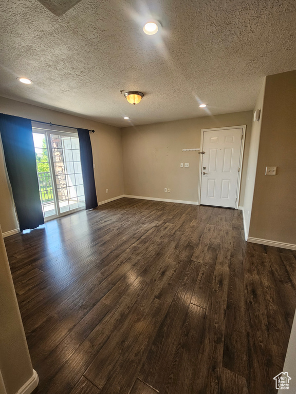 Unfurnished room with dark wood-type flooring, a textured ceiling, and recessed lighting
