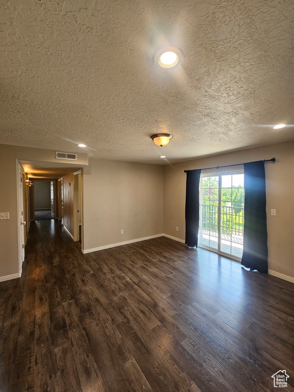 Empty room featuring dark wood-style floors and a textured ceiling