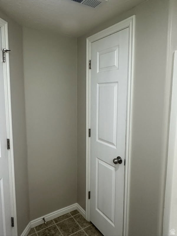 Interior space with baseboards and dark tile patterned flooring