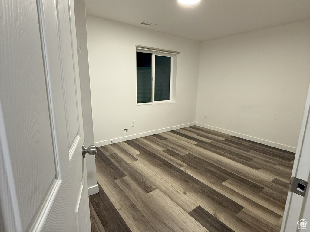 Unfurnished room featuring dark wood-type flooring and baseboards