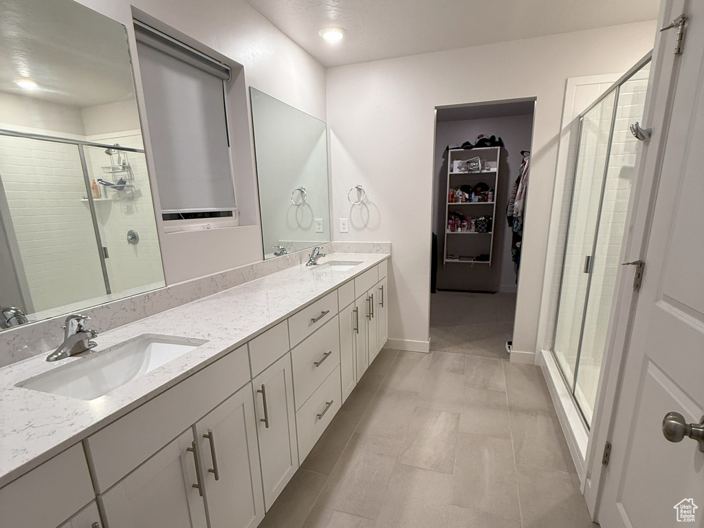 Full bath with a shower stall, double vanity, a spacious closet, and tile patterned flooring