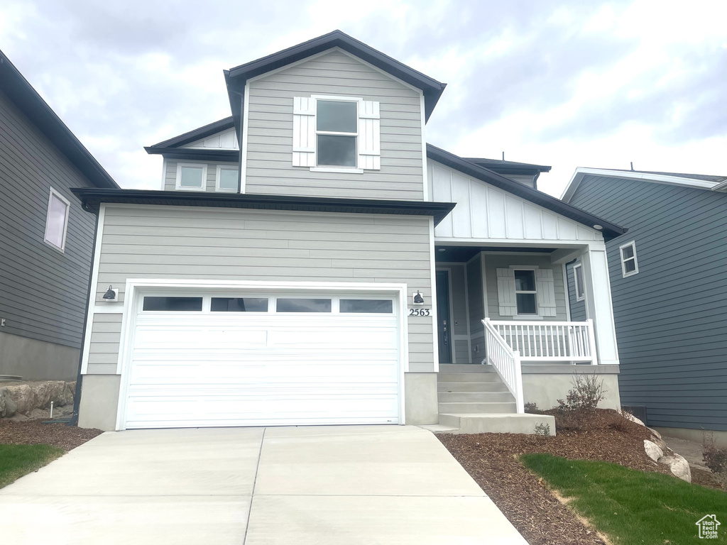 View of front facade featuring a porch, board and batten siding, concrete driveway, and a garage