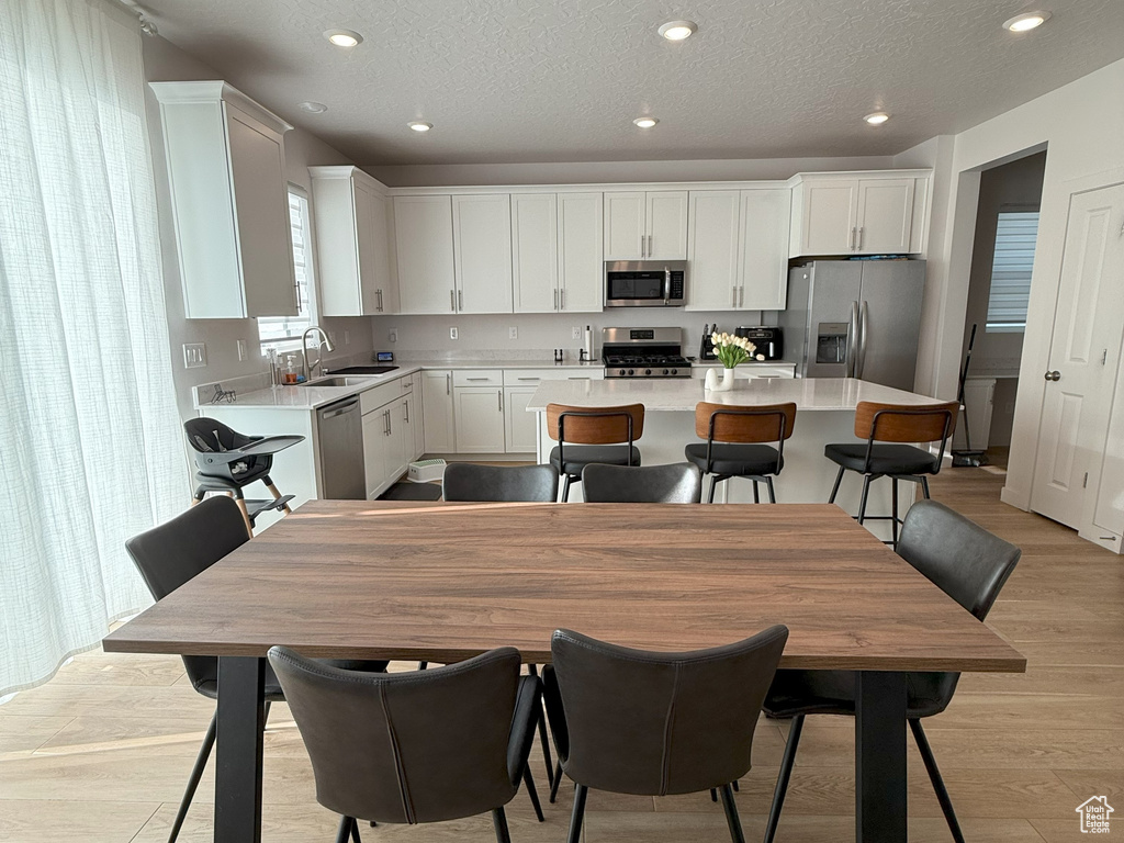 Dining room featuring light wood-type flooring, recessed lighting, and a textured ceiling