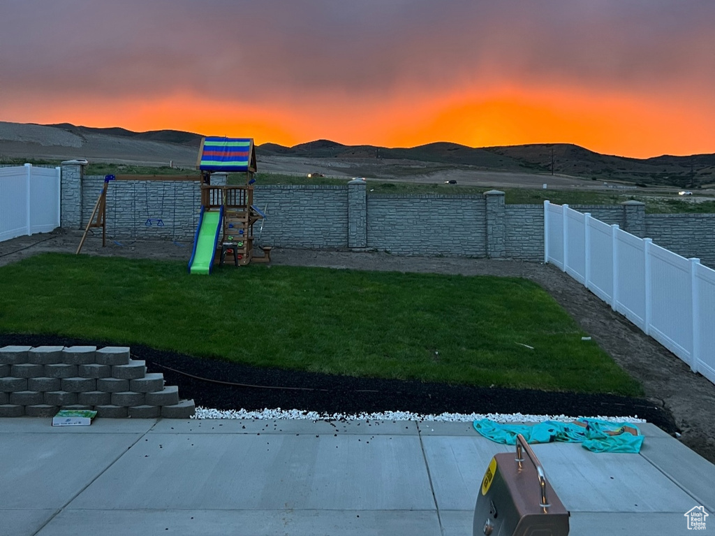 View of pool featuring a playground, a fenced backyard, and a mountain view