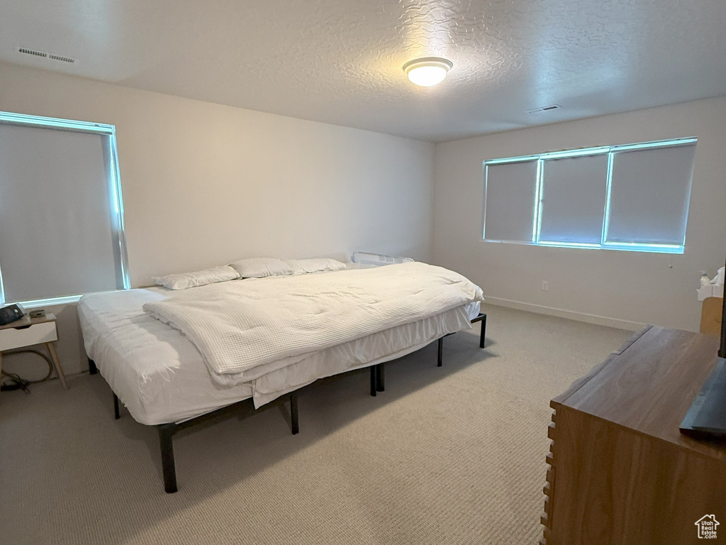 Carpeted bedroom featuring a textured ceiling and baseboards