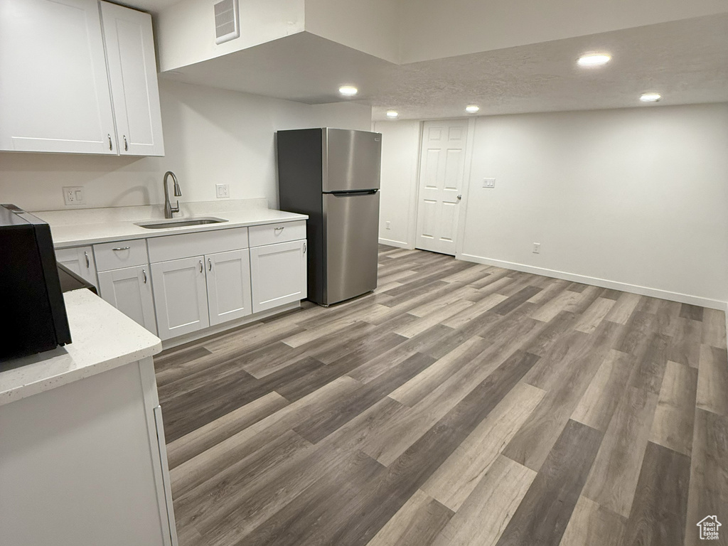 Kitchen with freestanding refrigerator, white cabinets, light countertops, recessed lighting, and wood finished floors
