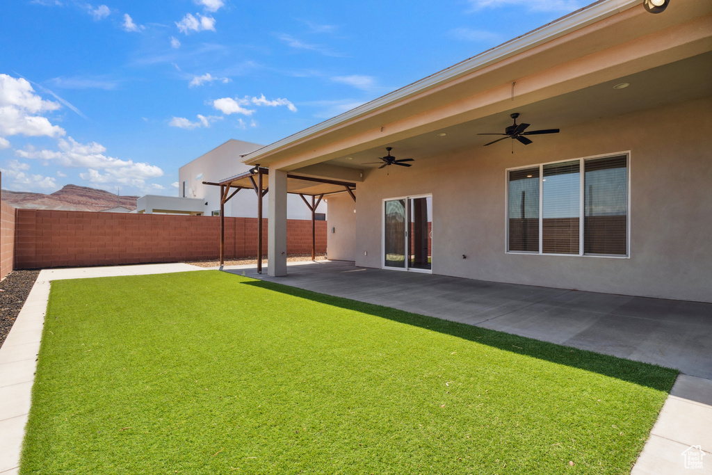 Fenced backyard with ceiling fan and a patio