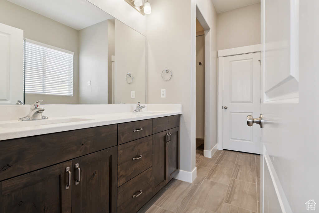 Full bathroom with double vanity and baseboards