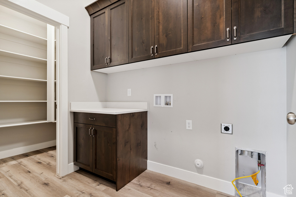 Laundry room featuring washer hookup, electric dryer hookup, light wood-style floors, cabinet space, and gas dryer hookup