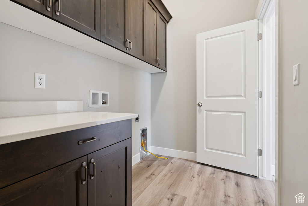 Laundry area featuring cabinet space, hookup for a washing machine, and light wood finished floors