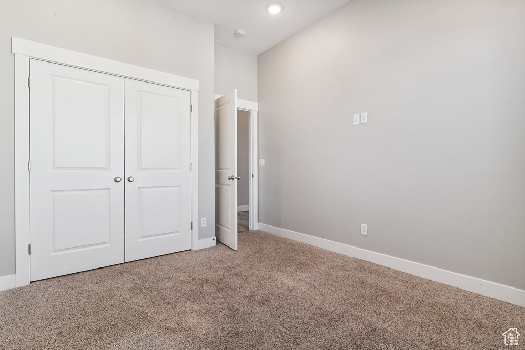 Unfurnished bedroom with light carpet and a closet