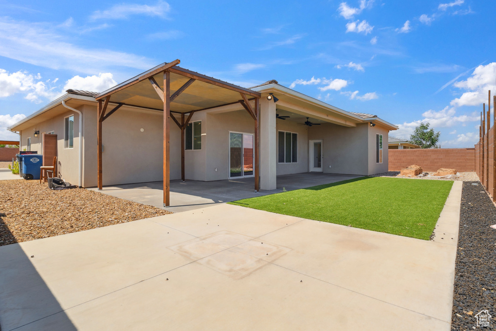 Back of property with a ceiling fan, a fenced backyard, stucco siding, and a patio area