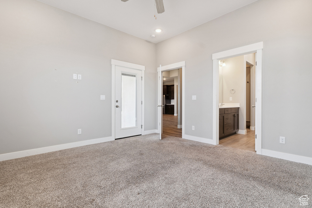Unfurnished bedroom featuring light colored carpet, connected bathroom, and ceiling fan
