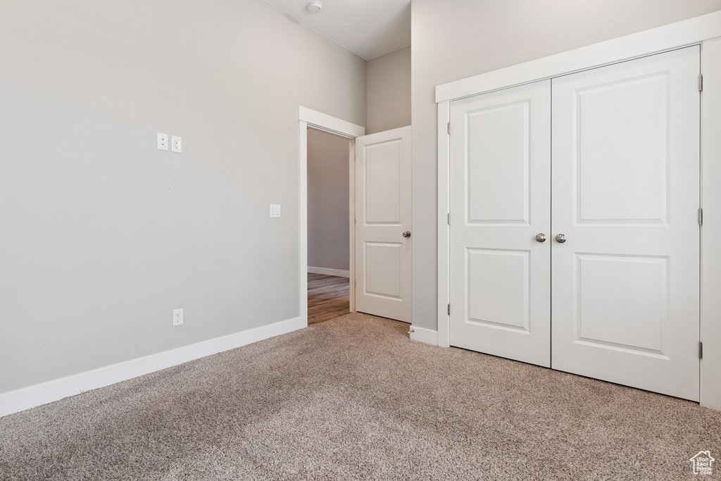 Unfurnished bedroom with light colored carpet and a closet
