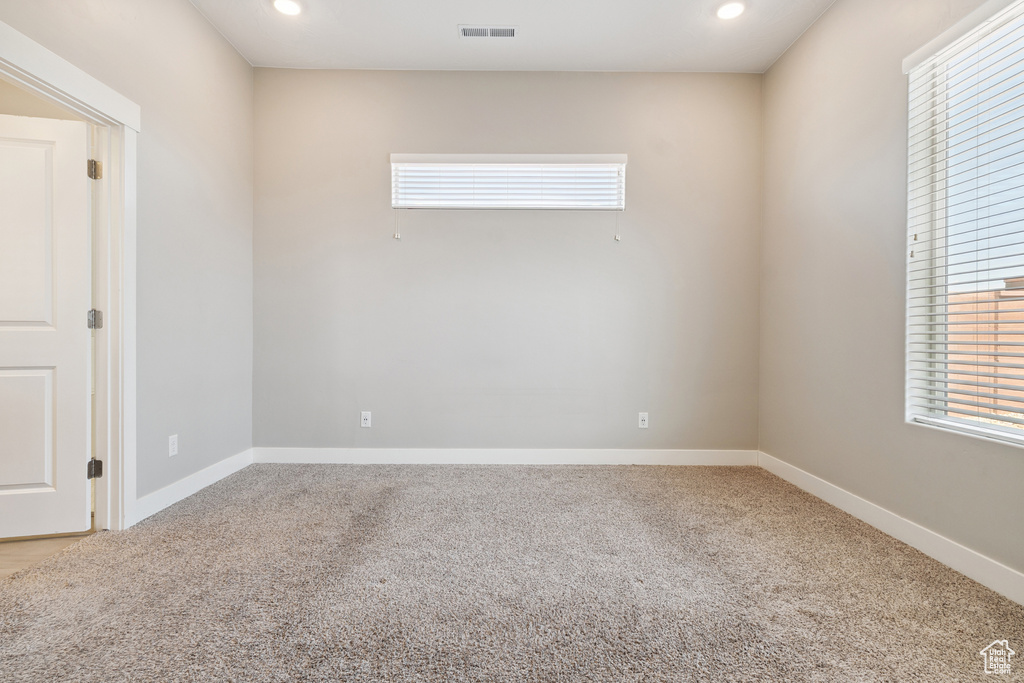 Carpeted empty room with plenty of natural light and recessed lighting