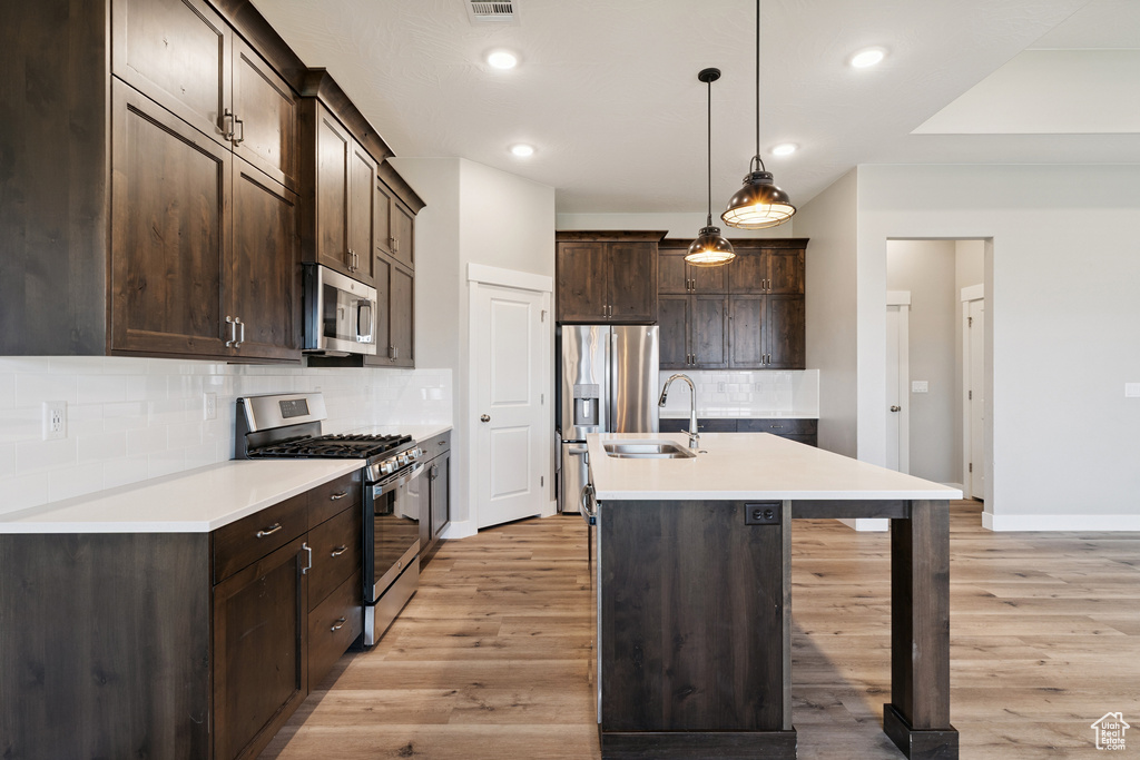 Kitchen featuring stainless steel appliances, dark brown cabinets, light wood-style floors, and recessed lighting