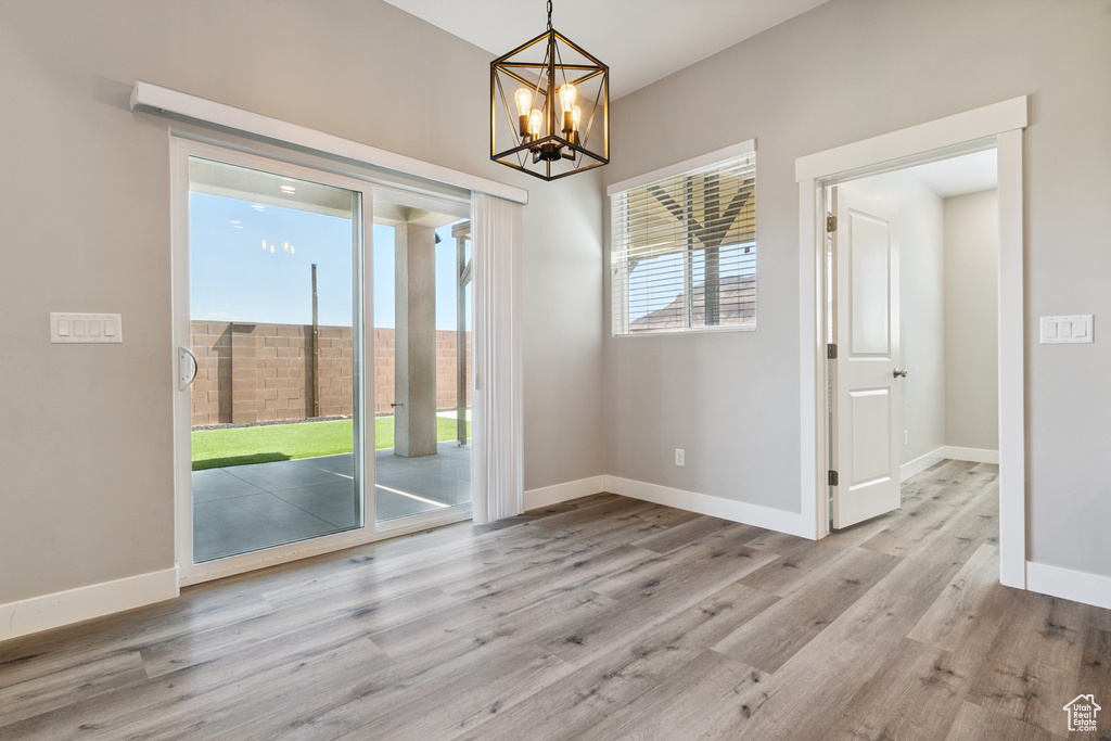 Unfurnished room featuring wood finished floors and a chandelier
