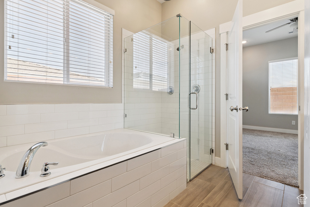 Full bathroom with a garden tub, a stall shower, plenty of natural light, and wood finished floors
