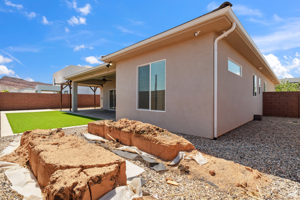 Rear view of house with ceiling fan, a fenced backyard, a patio area, and stucco siding