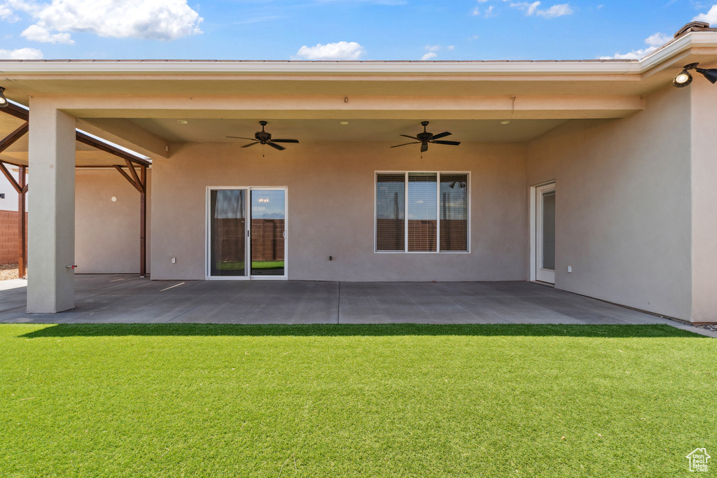 Back of property with a ceiling fan, a patio area, stucco siding, and a lawn