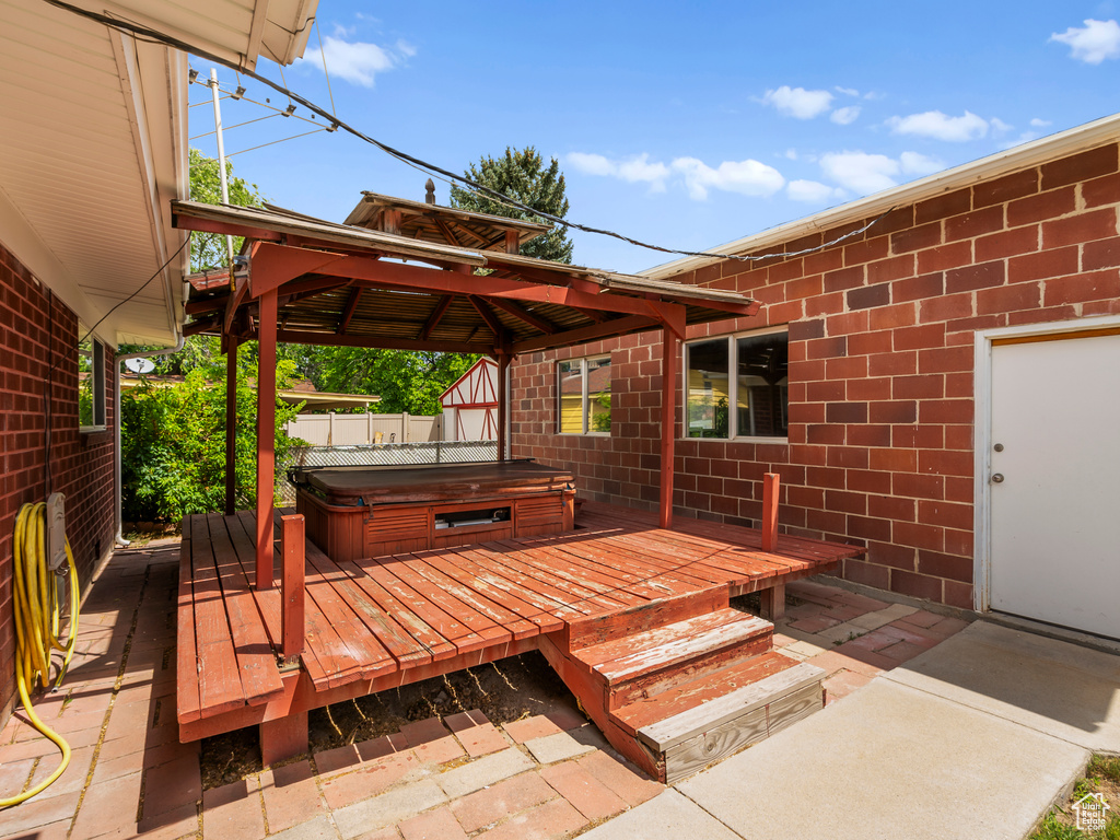 Wooden deck with a covered hot tub, a gazebo, and a patio