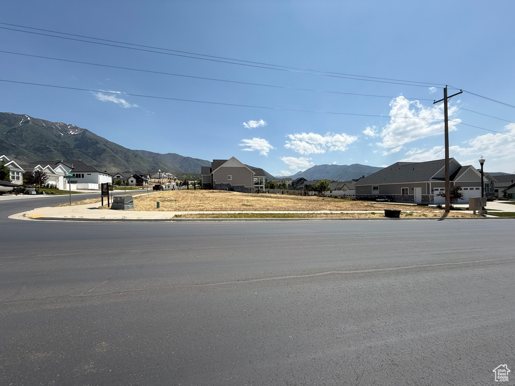 View of asphalt road featuring sidewalks, a mountain view, curbs, and a residential view