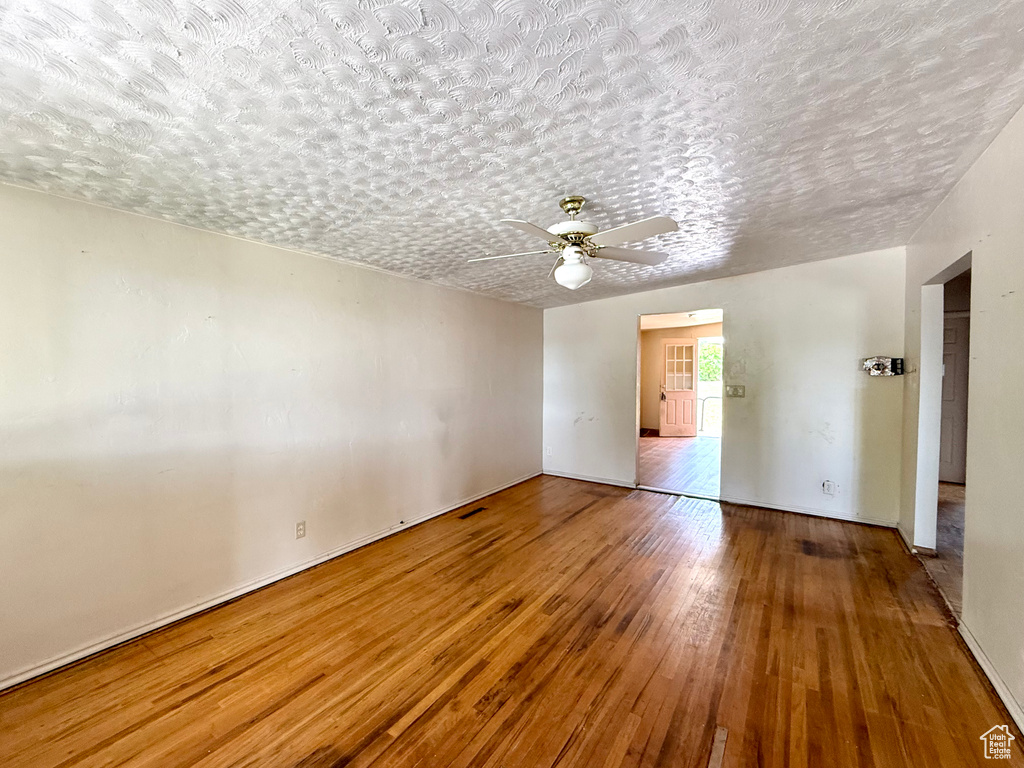 Spare room with hardwood / wood-style floors, ceiling fan, and a textured ceiling