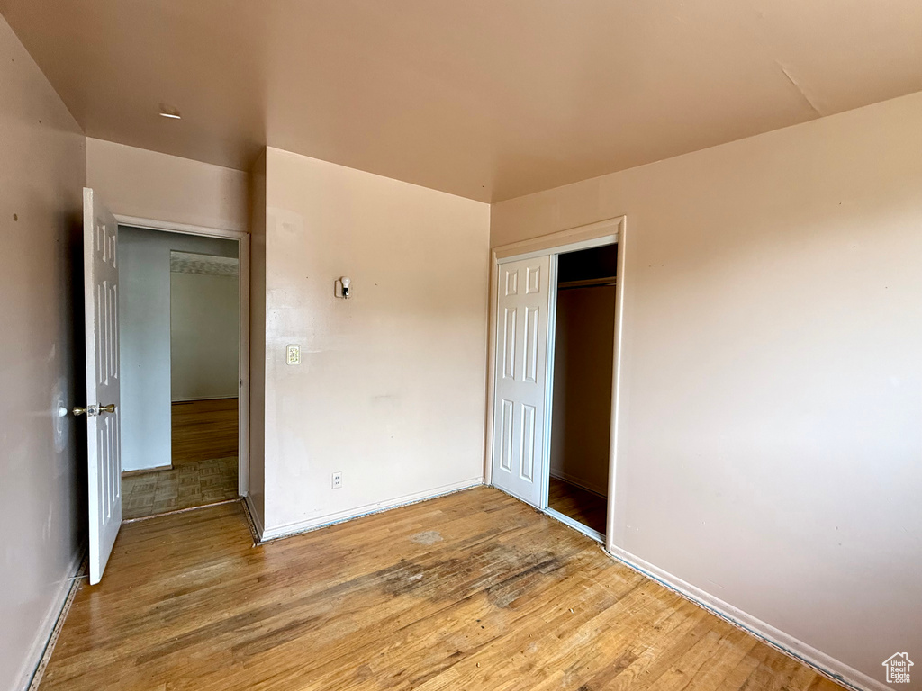 Unfurnished bedroom with wood finished floors and a closet