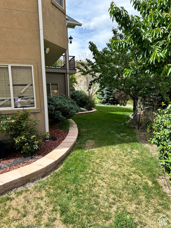 View of grassy yard with a balcony