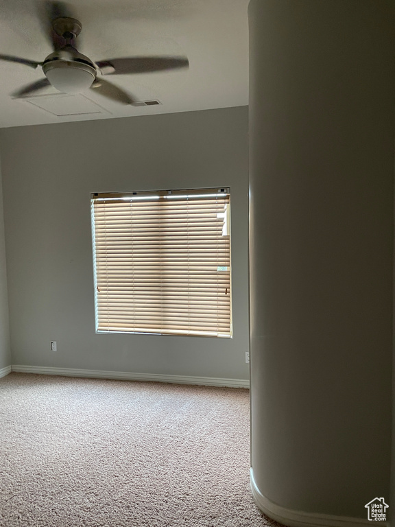 Carpeted empty room featuring a ceiling fan and baseboards