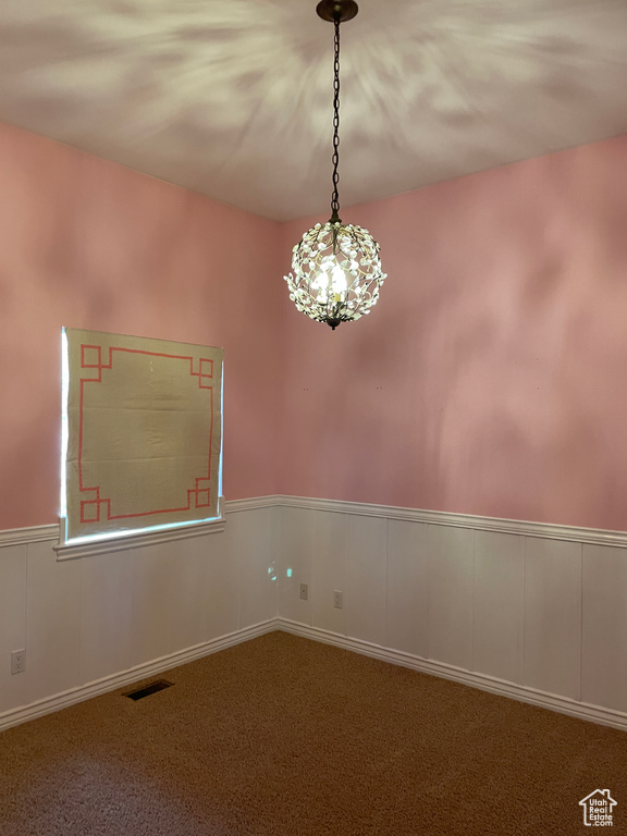 Spare room with carpet floors, wainscoting, and a chandelier