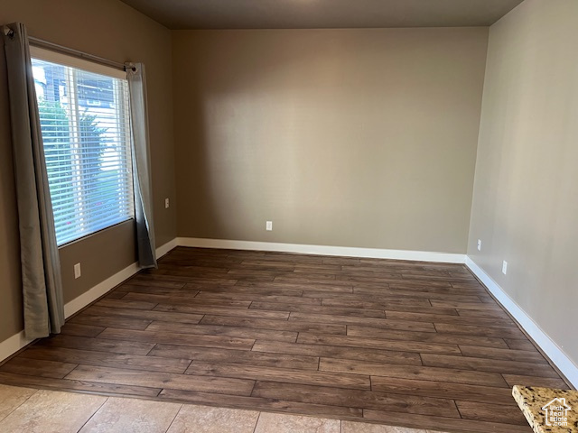 Empty room with dark wood-style flooring and baseboards