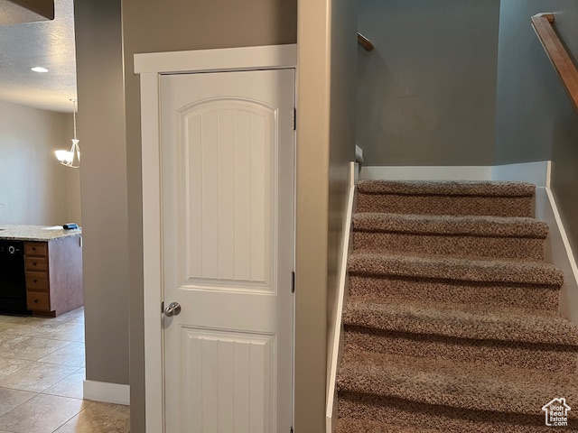 Stairs featuring a textured ceiling, tile patterned floors, and recessed lighting